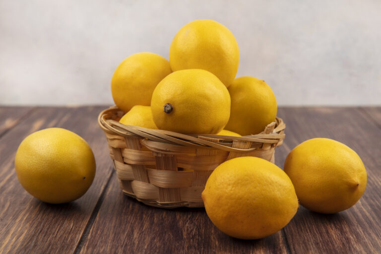 Side View Of Fresh Yellow Skinned Lemons On A Bucket With Lemons Isolated On A Wooden Table On A White A White Background