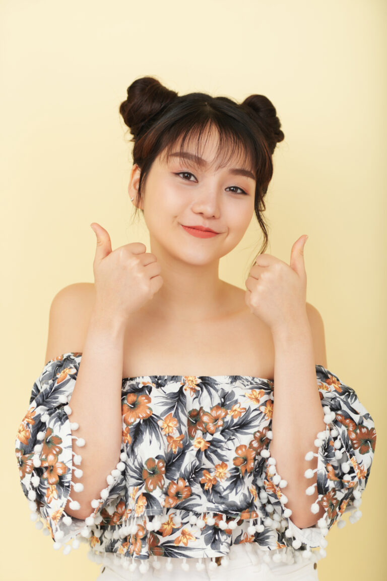 Smiling Asian Girl Bare Shoulder Top Posing Studio With Thumbs Up